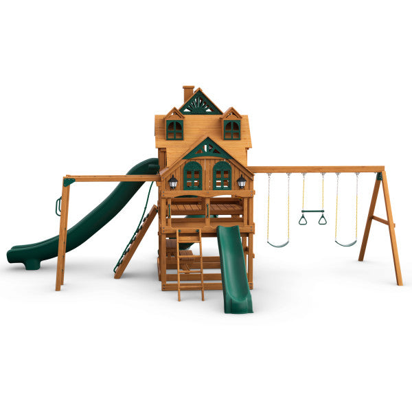 Cedar wooden playset with three decks, green slides, swings, climbing ladder, and trapeze bar.