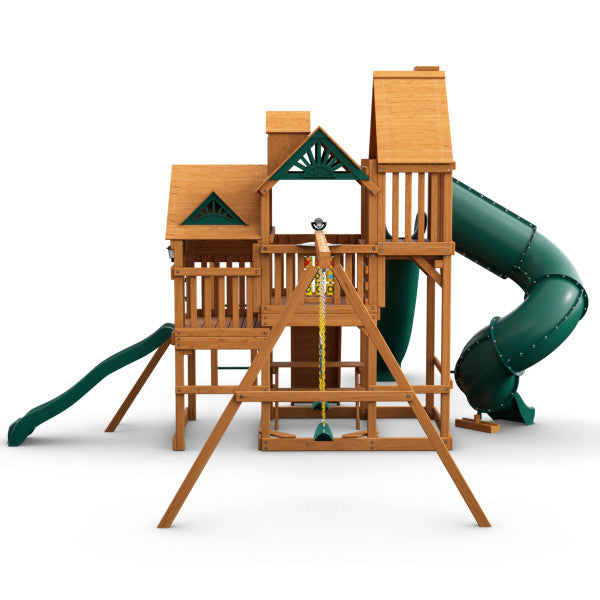 Cedar wooden playset with three decks, green spiral and straight slides, swings, climbing wall, and monkey bars