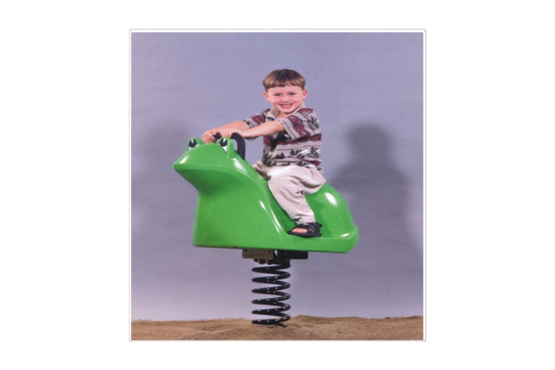 Frog Spring Rider playground equipment with bright green frog design and black spring base on sandy surface