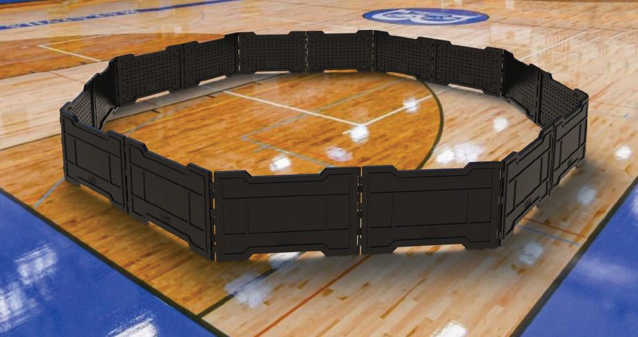 Black modular GaGa ball pit panels arranged in a large octagonal shape on a gym floor