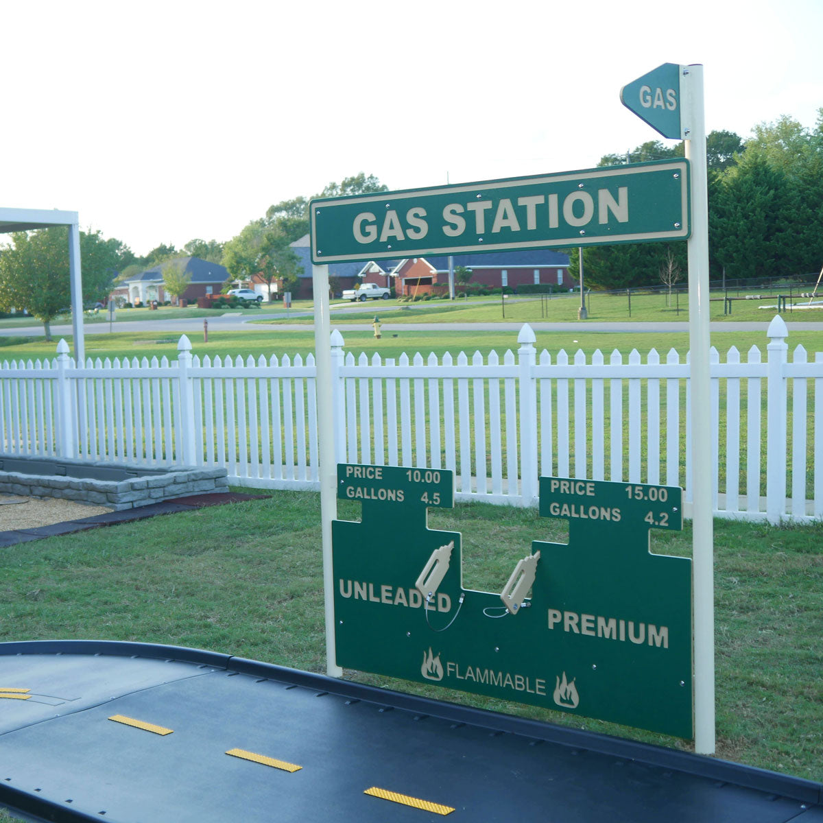 Green and beige commercial playground gas station playset with fuel pump handles and price signs on grass