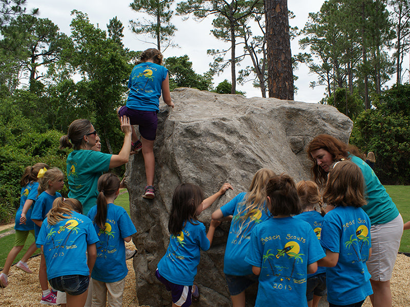 Giant's Chair Climbing Boulder with children climbing and gathered around natural rock-like outdoor play structure