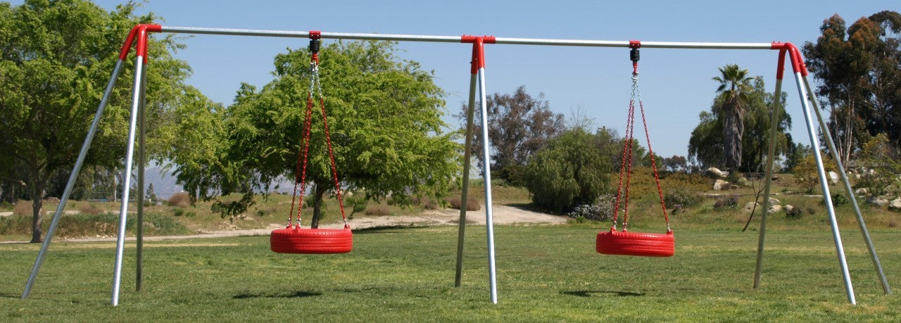 Heavy-duty metal swing set with two red tire swings suspended by chains in a grassy park setting