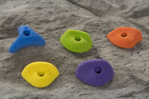 Colorful blue, green, orange, yellow, and purple climbing handholds mounted on a textured modular climbing panel surface