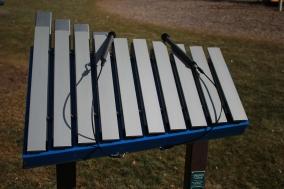 Outdoor blue metal musical instrument with eleven aluminum bars and attached mallets on a stand, designed for parks and playgrounds