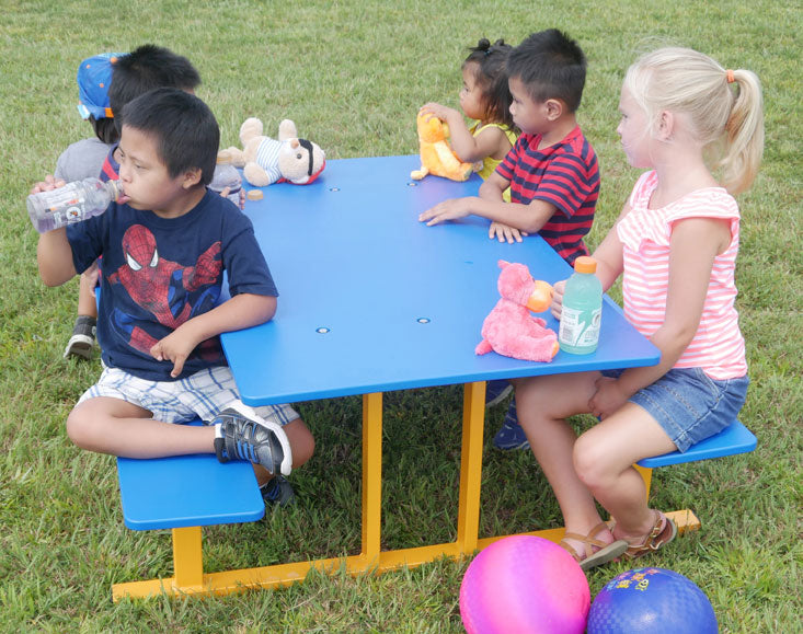 Preschool Picnic Table with blue HDPE top and yellow metal frame, children seated outdoors on grass with toys and drinks