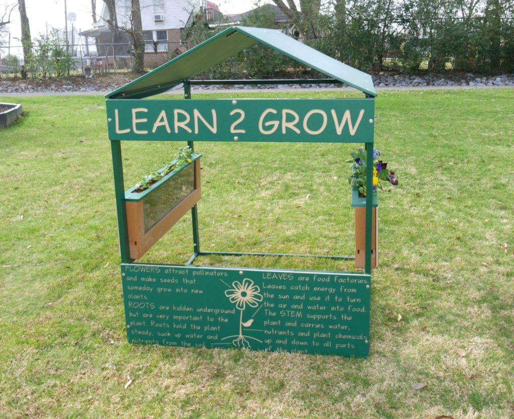 Green educational playhouse with clear root view planters and flower boxes, outdoor garden learning equipment on grass