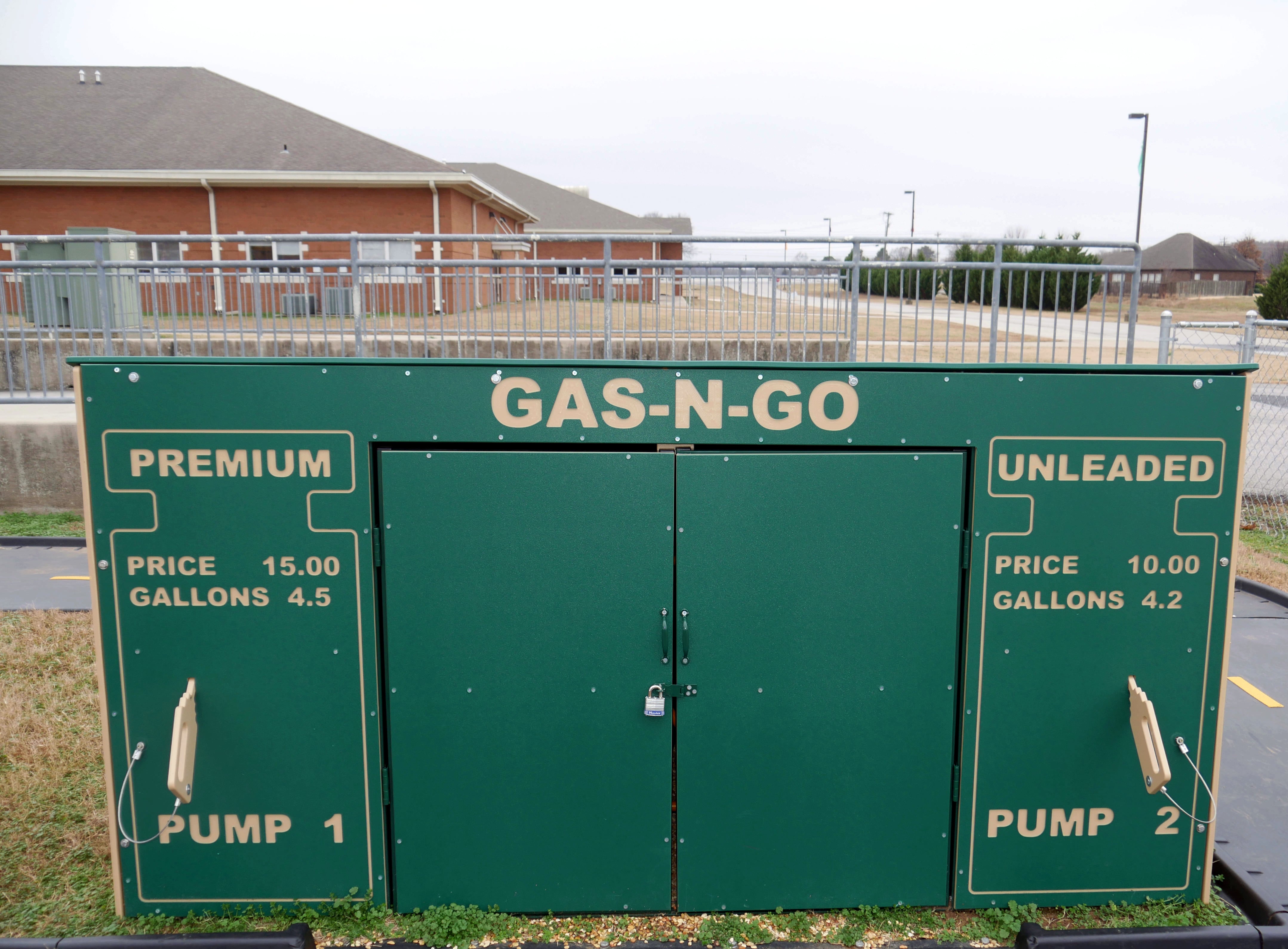 Green outdoor lockable storage unit shaped like a gas pump with two doors and safety padlock for playground tricycle storage