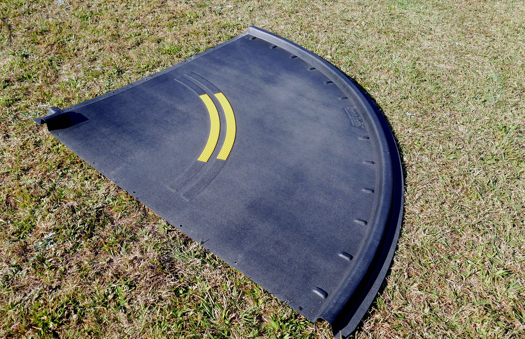 Curved black trike path segment with yellow road markings on grass, designed for playground racetrack extension