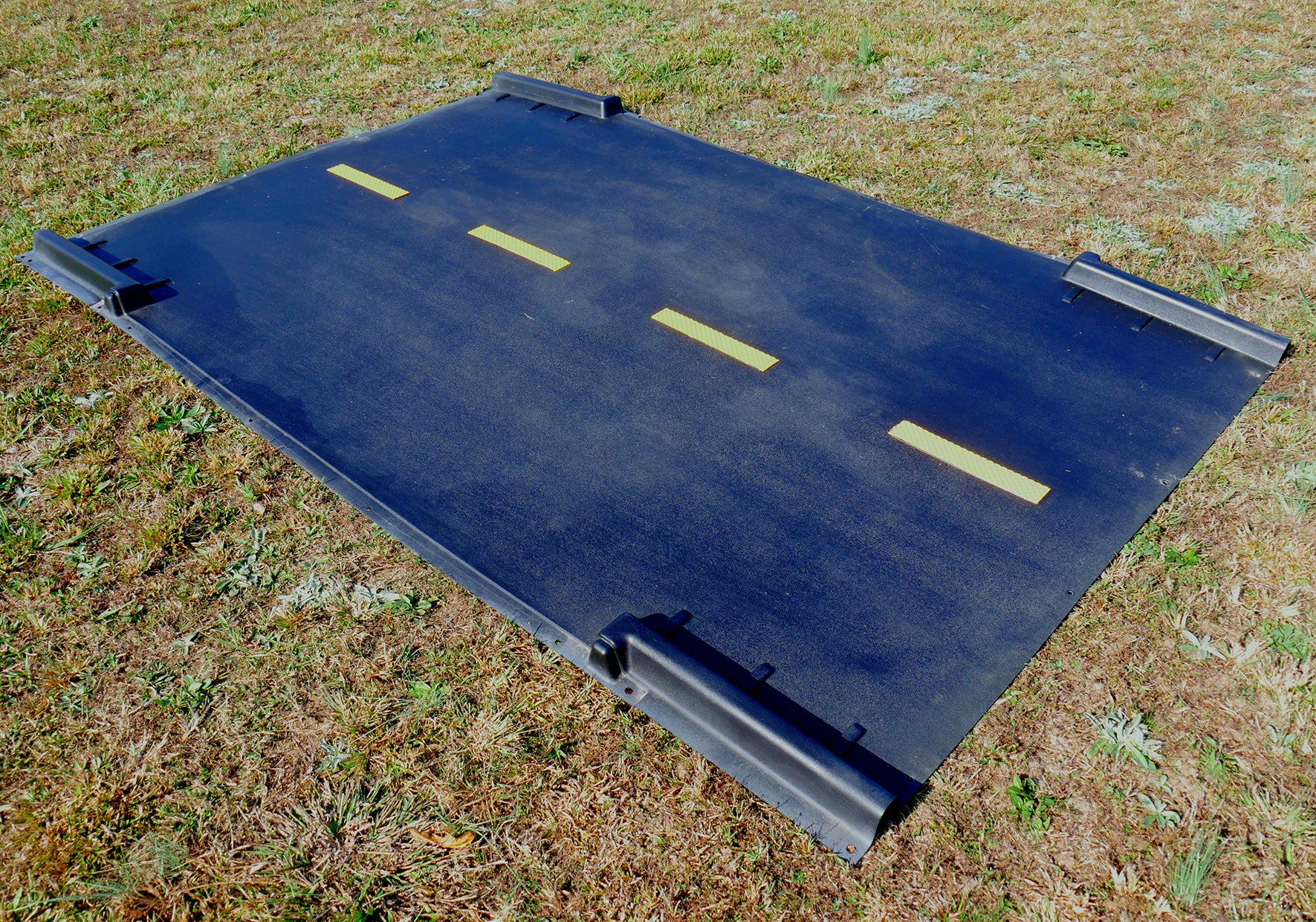 Black textured playground racetrack intersection piece with yellow dashed lines and raised edges for trike path extension