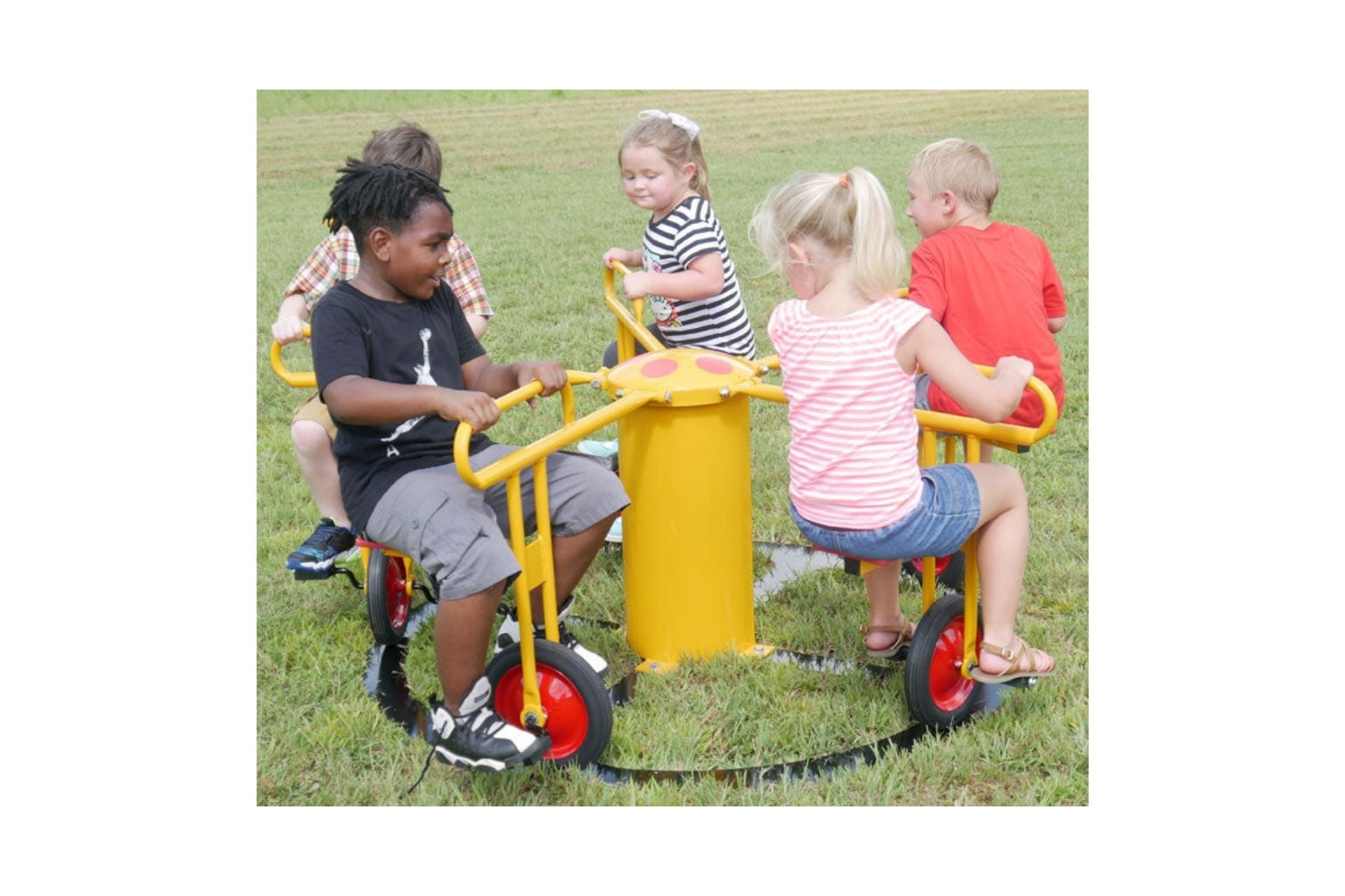 Children riding a yellow inground cycle seat play rider with red wheels on grass outdoors