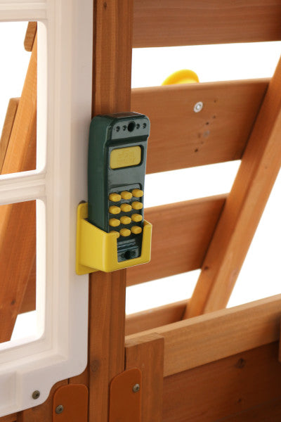 Toy play phone mounted on natural wood panel wall with white window frame on wooden playset