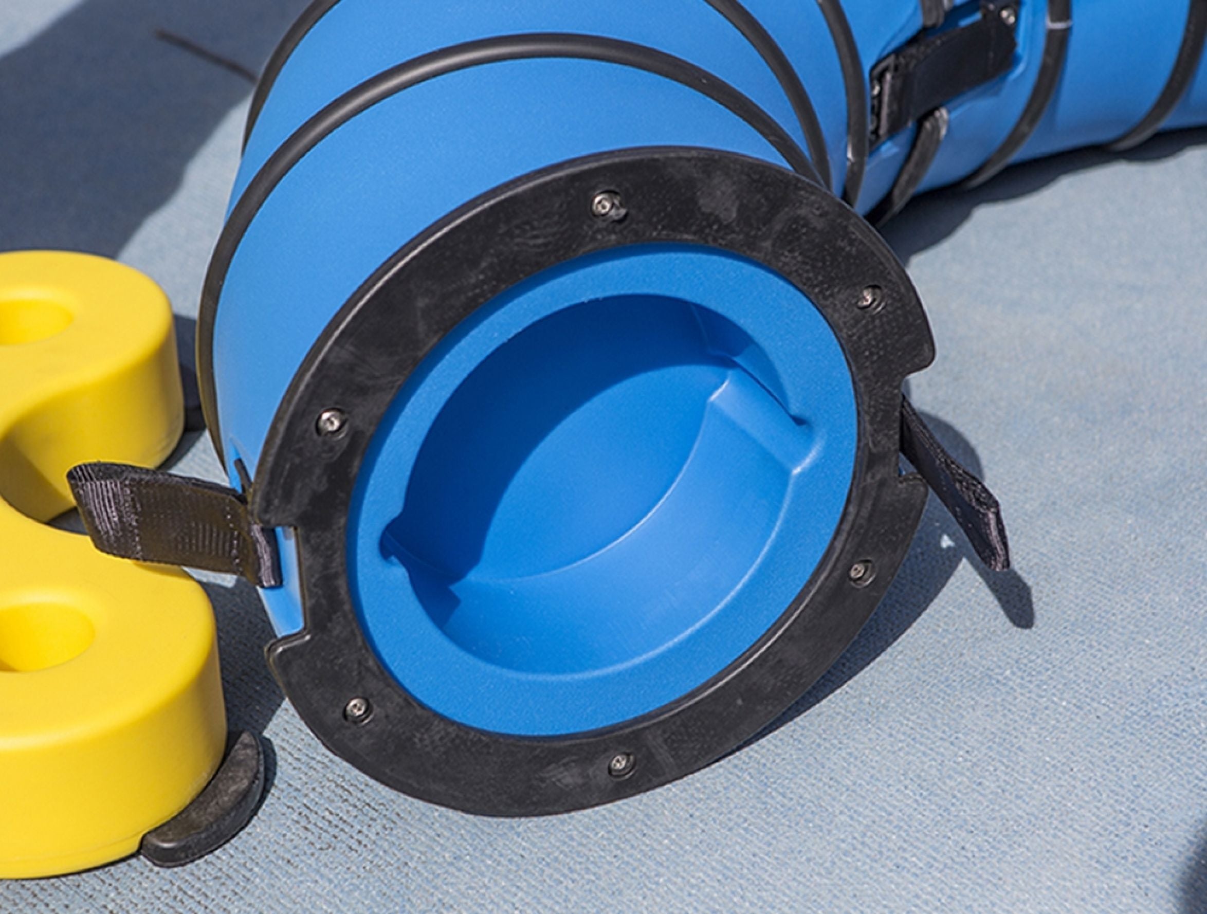Blue interactive play ring with black rim and yellow play pieces on textured outdoor surface