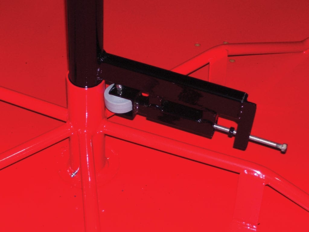 Red powder-coated steel merry go round deck with black speed governor and metal bolt for controlled rotation