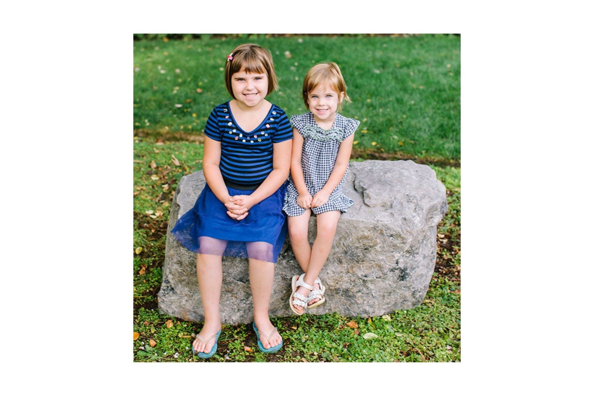 Mesa Rock Bench with natural rock texture, two children sitting on green grass, versatile outdoor park bench and climber