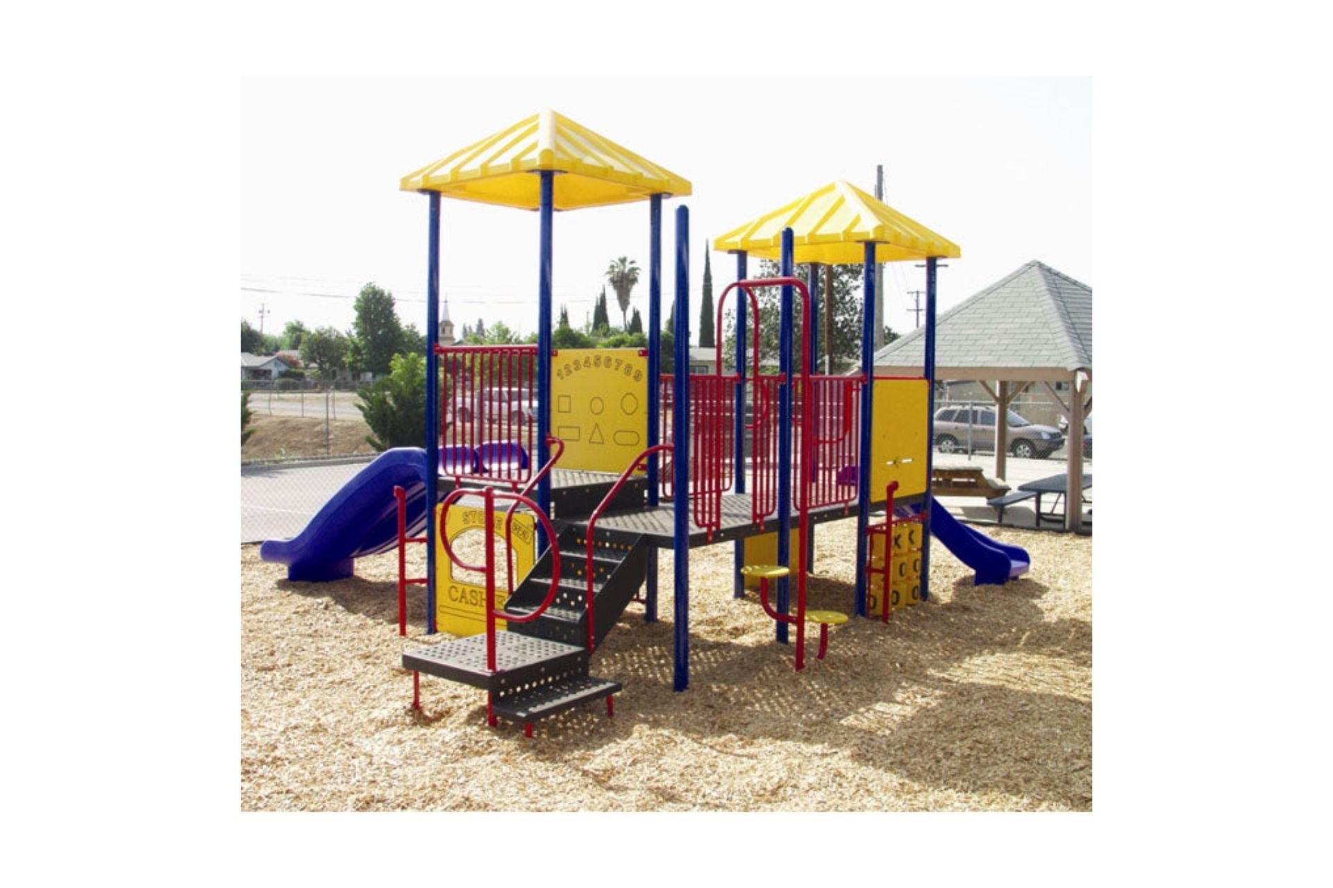 Miss Jenna Modular Playground with yellow roofs, blue slides, red railings, interactive panels, and wood chip ground