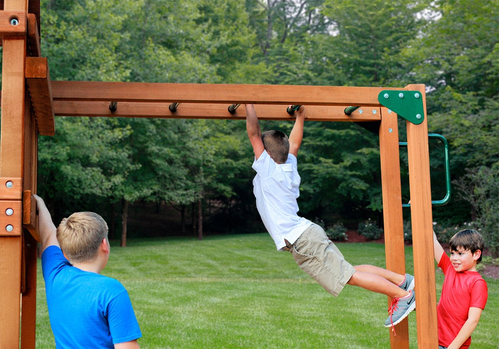 Cedar amber-finished monkey bars attached to wooden swing set with three boys playing on green lawn outdoors
