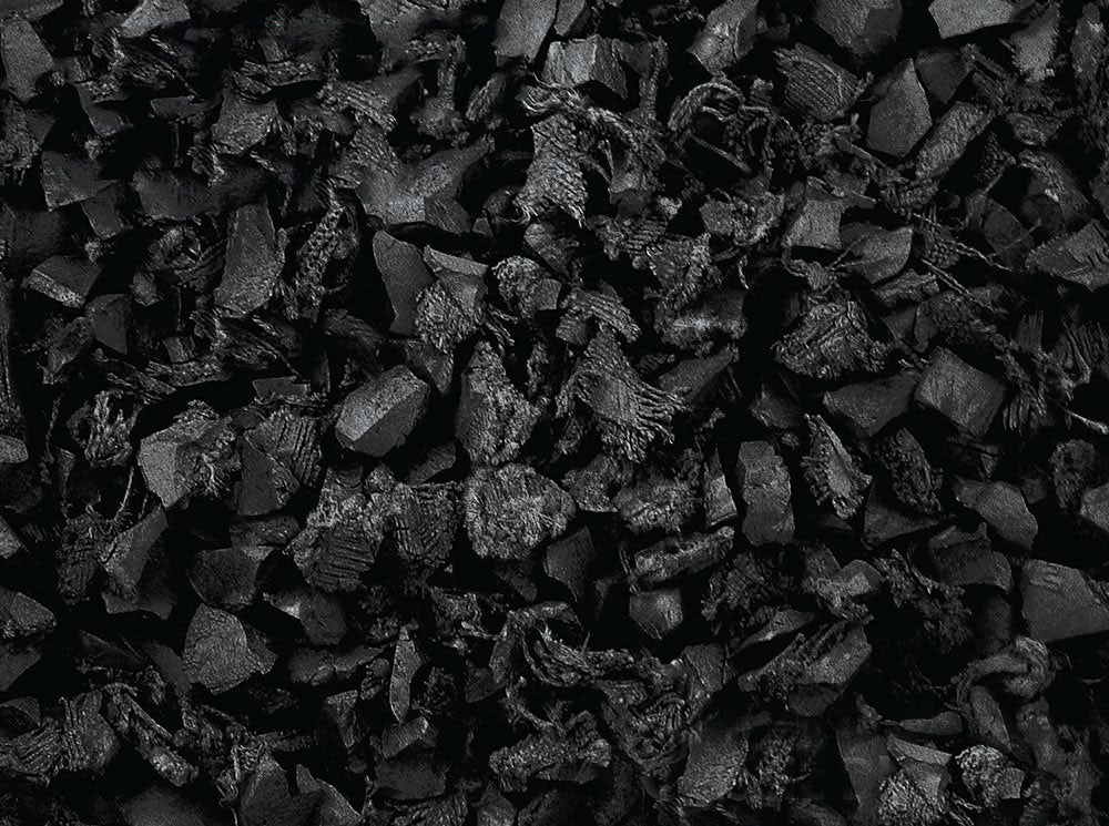Close-up of irregularly shaped black recycled rubber playground mulch pieces with textured, shock-absorbing surface