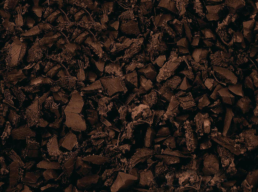 Close-up of dark brown recycled rubber playground mulch pieces with varied shapes and textured surfaces