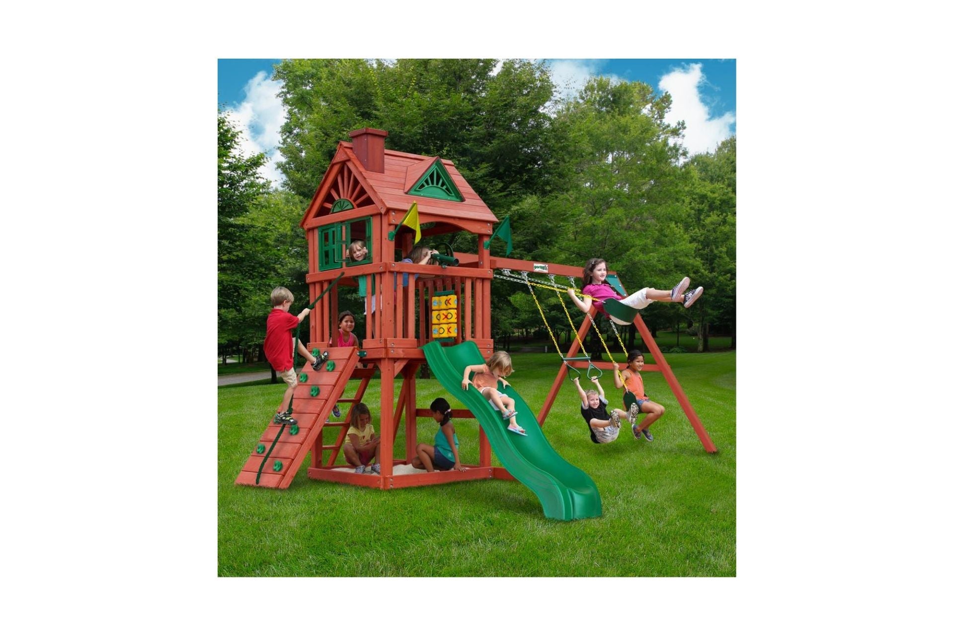 Redwood-stained wooden playset with clubhouse, green wave slide, rock climbing wall, swings, and children playing outdoors