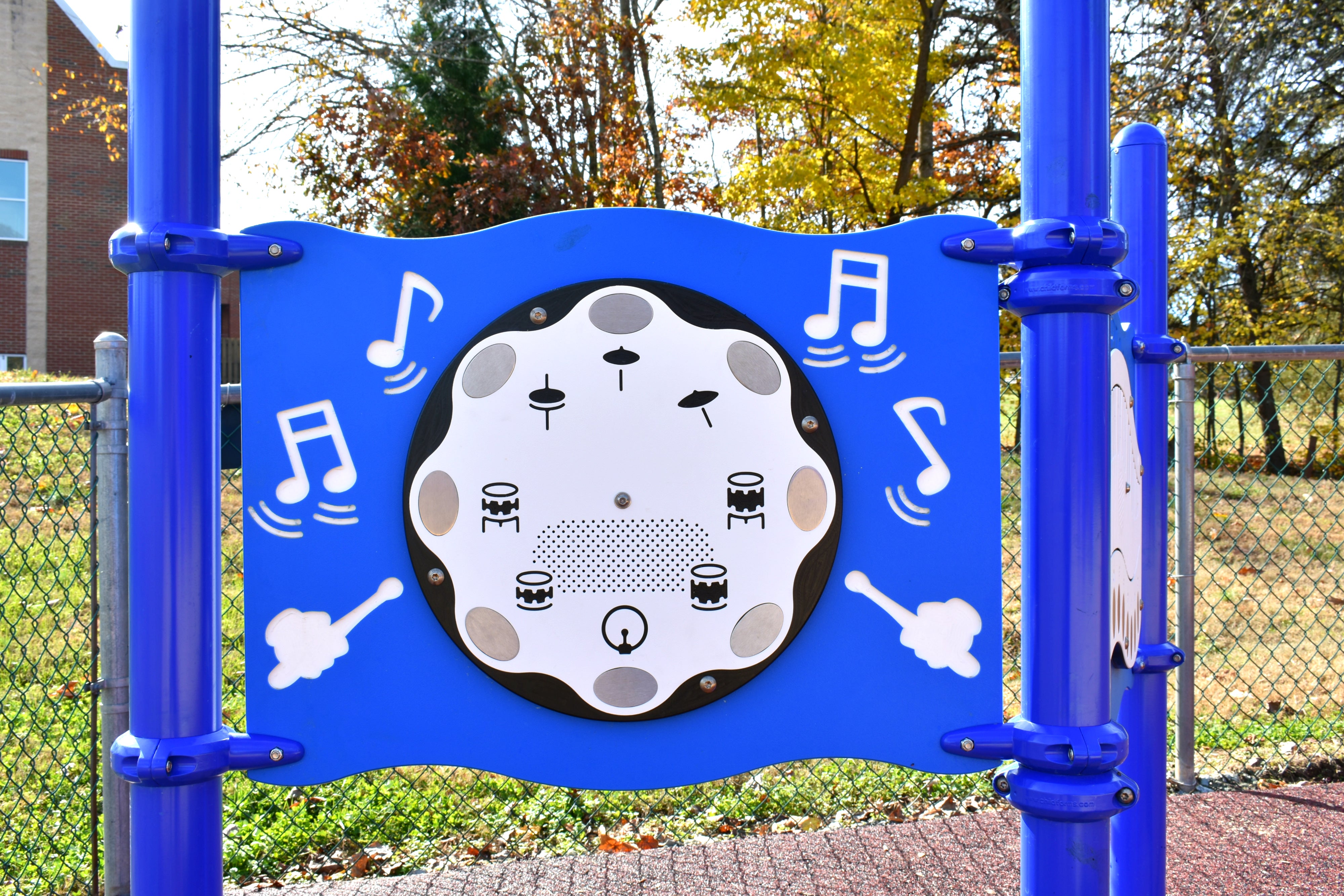 Drum Panel Interactive Music Station with blue frame and white drum pad featuring musical notes and drum icons in outdoor playground setting