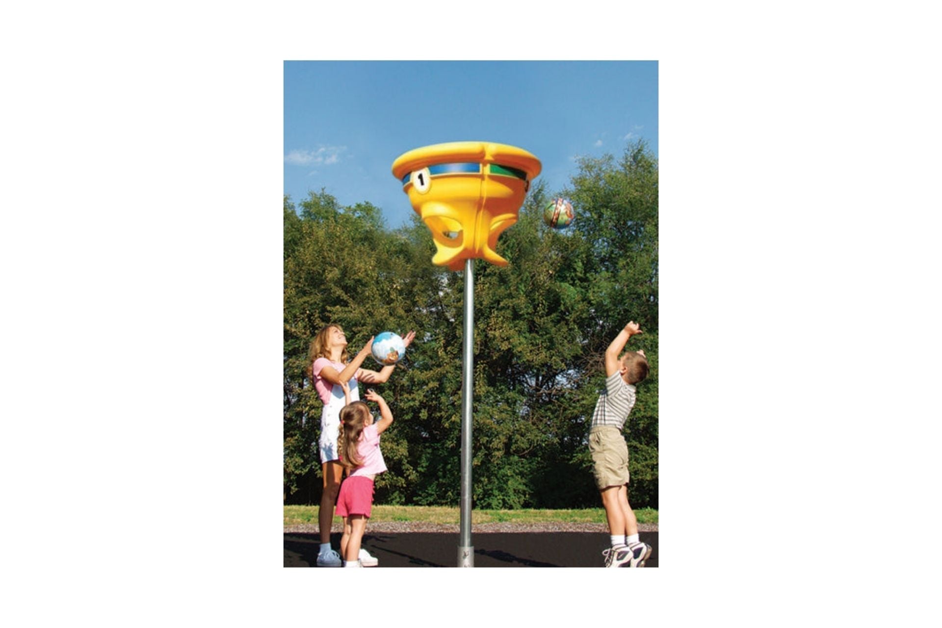 Colorful yellow funball hoop on a tall metal pole in an outdoor playground surrounded by trees with children playing nearby