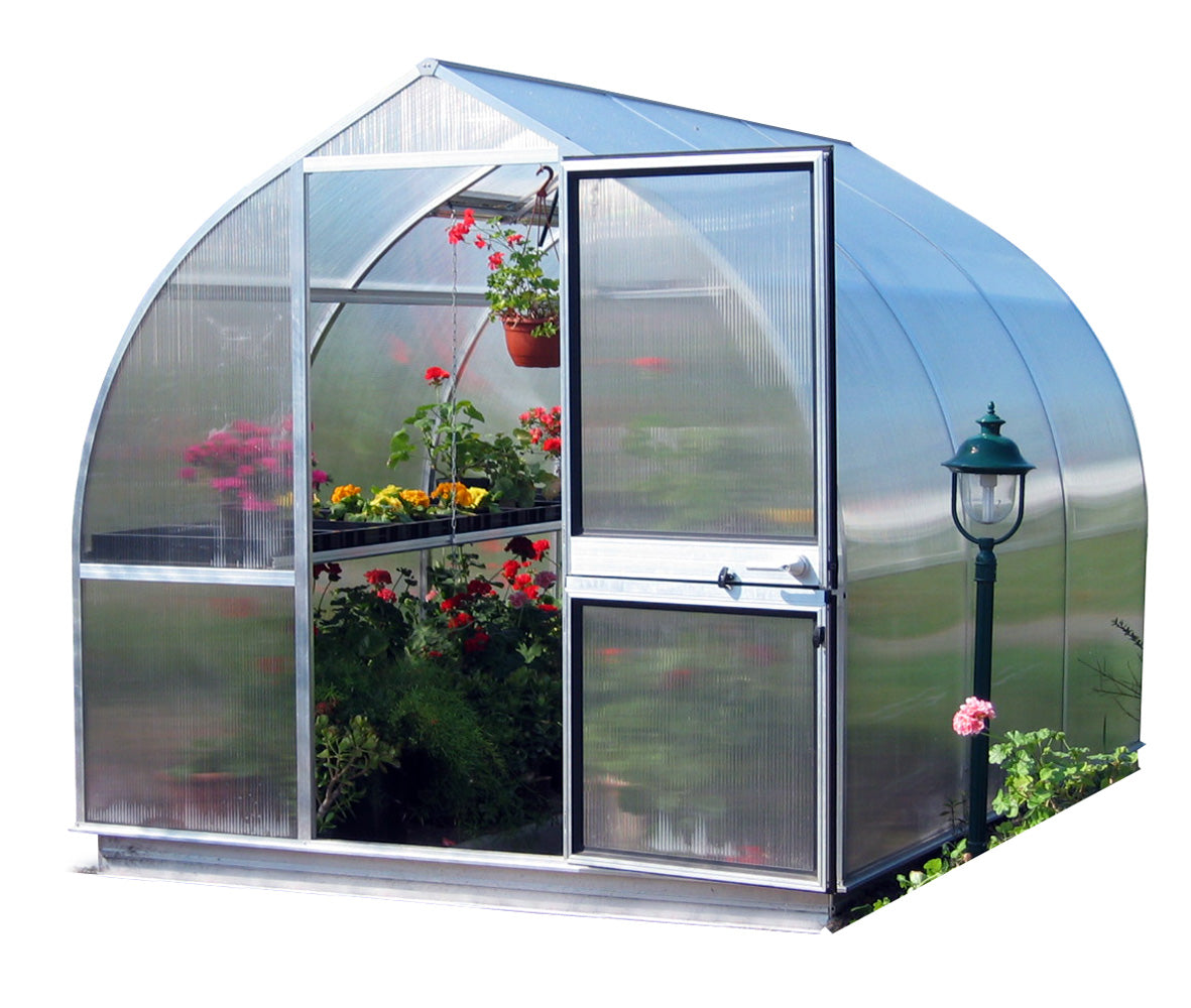Curved polycarbonate greenhouse with colorful flowering plants, barn-style door open, and nearby garden lamp