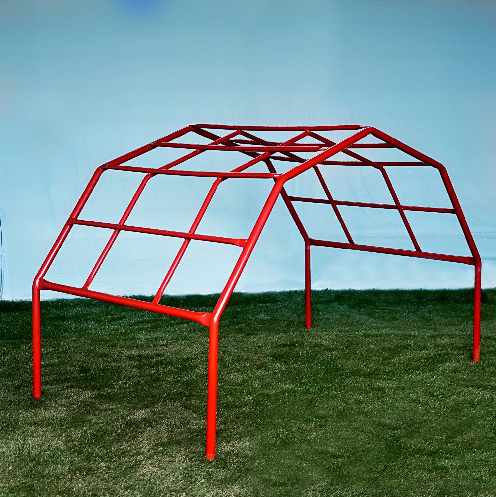 Red powder-coated steel climbing frame with angled bars on grass for children's physical play and agility.