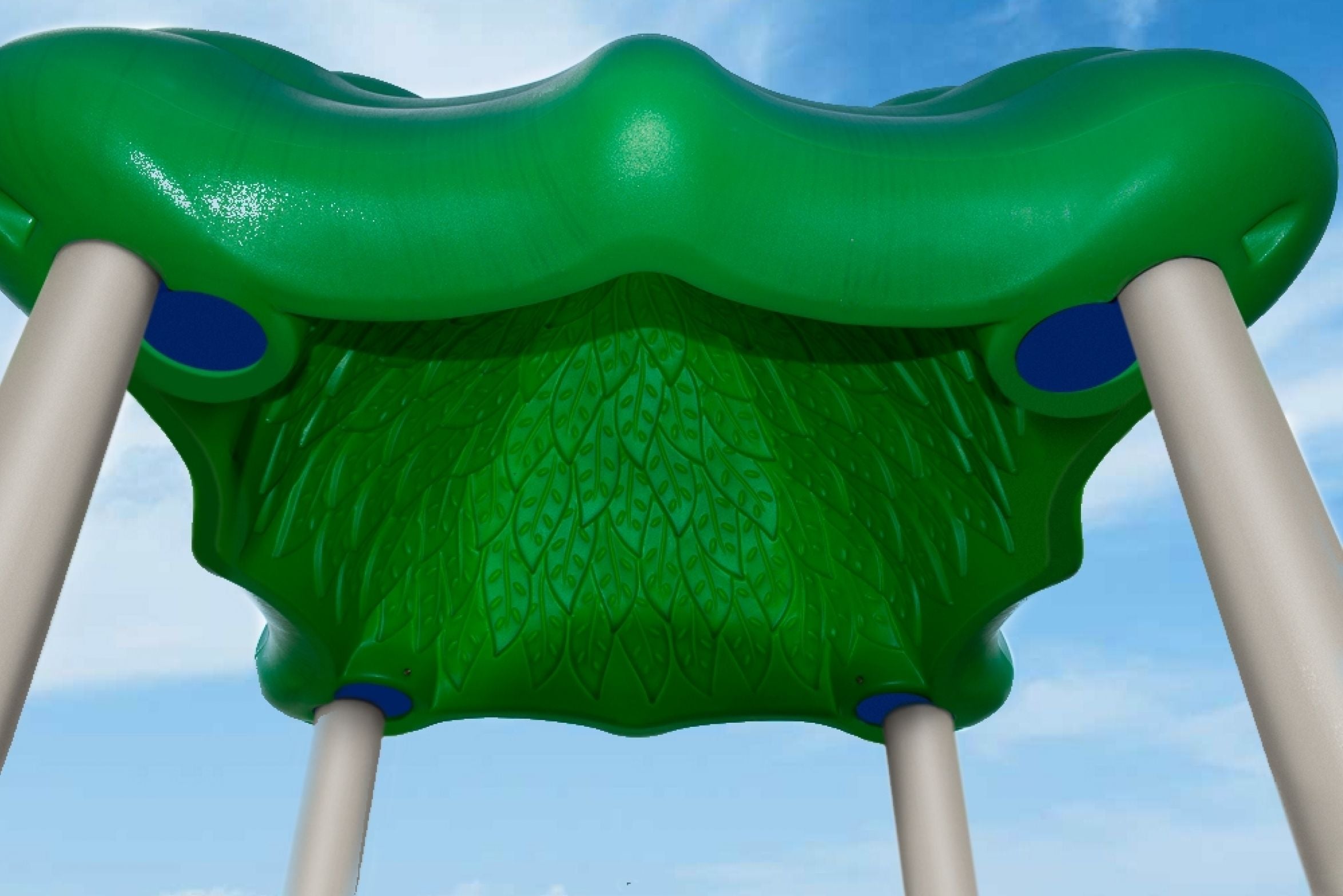 Underside view of green leaf-patterned playground canopy supported by beige posts against blue sky