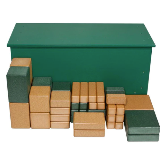 Green and tan eco-friendly foam blocks of various sizes arranged in front of a green storage bench for creative play