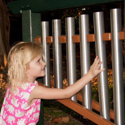 Child playing outdoor musical chime unit with aluminum tubes and recycled plastic frame in a park setting