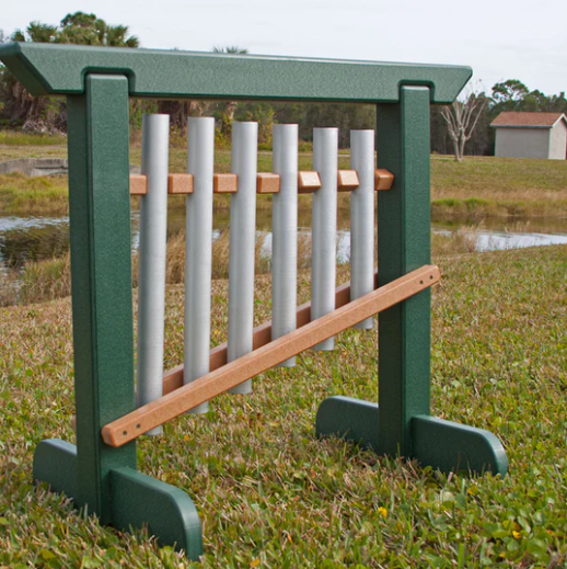 Outdoor musical chime unit with six aluminum tubes in a green recycled plastic frame on grass