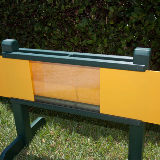 Outdoor planter with green recycled plastic frame, yellow sliding panels, and clear polycarbonate windows for root observation.