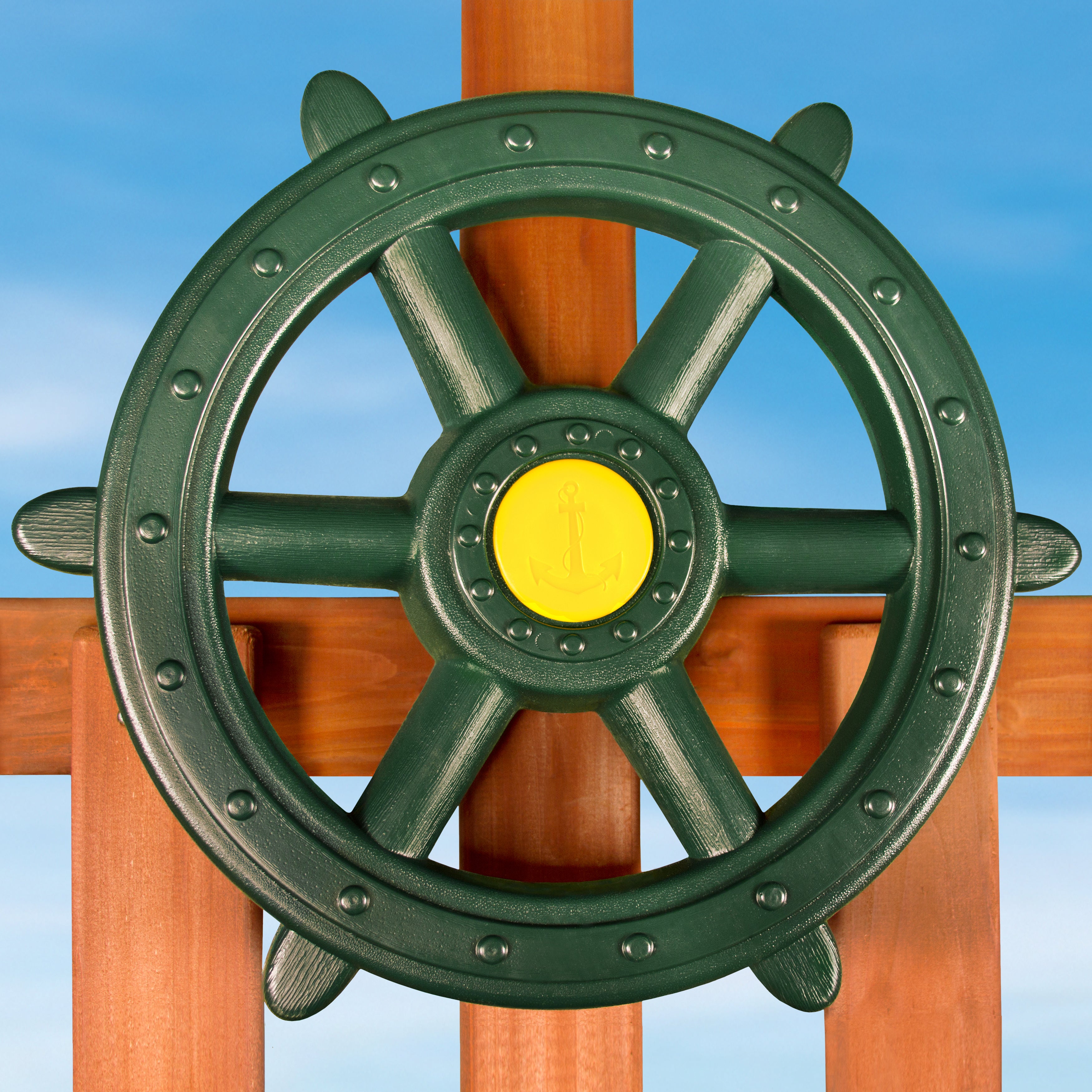 Large green heavy-duty plastic Ship's Wheel Swing Set Accessory with yellow anchor center mounted on wooden playset against blue sky