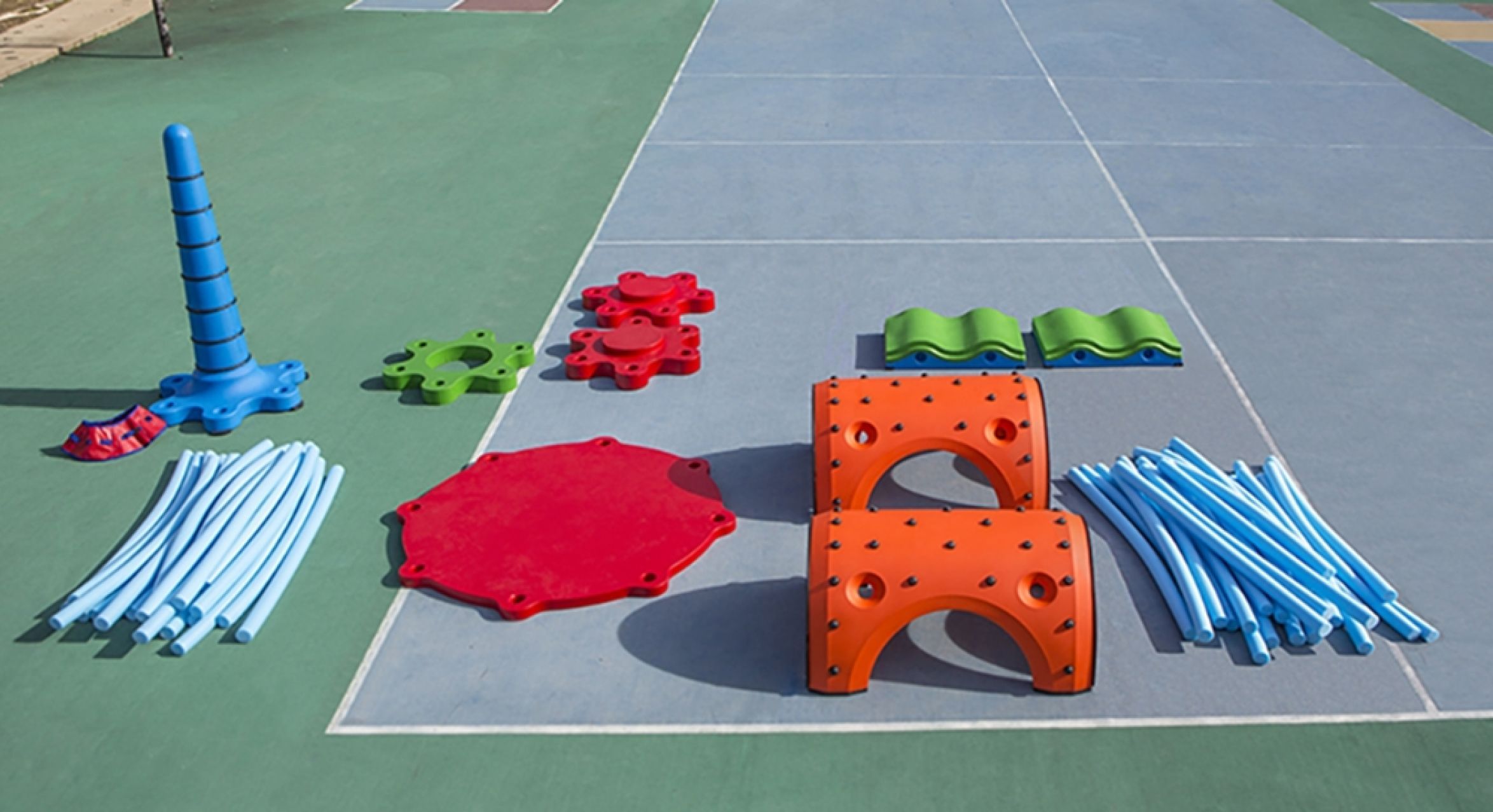 Colorful modular outdoor play equipment with blue tubes, orange arches, red platforms, and green connectors on playground surface