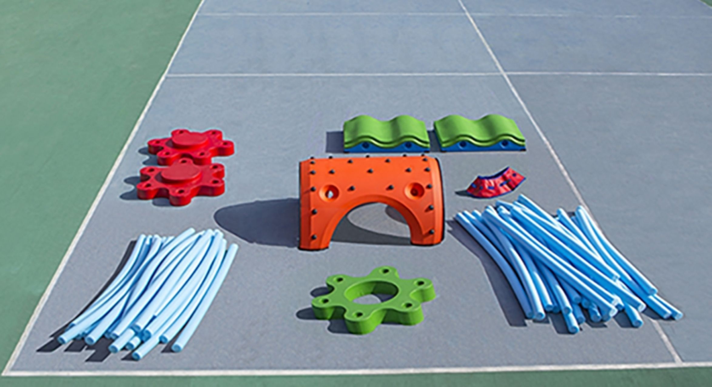 Colorful modular outdoor play equipment with red and green connectors, blue flexible rods, and an orange climbing arch on a court surface