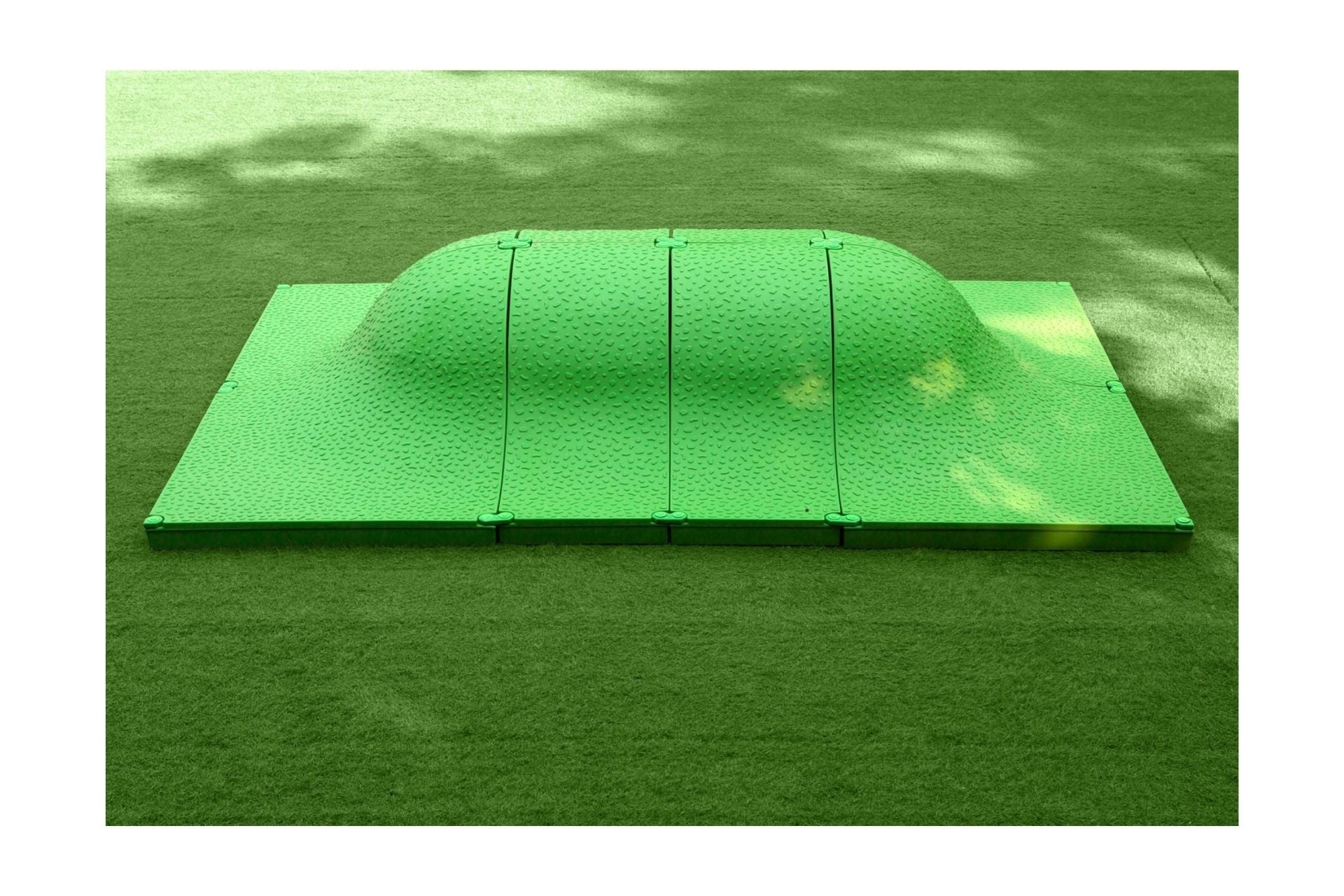 Green textured curved play mound on artificial grass, designed for interactive outdoor children's play and exploration