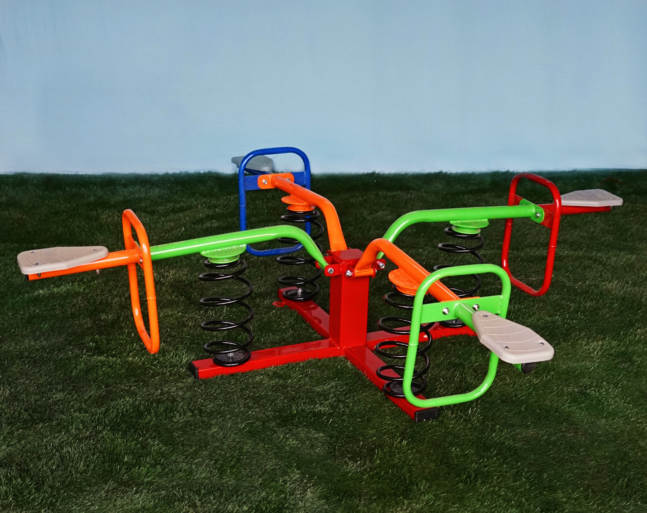 Colorful four-seat spring rider playground toy with metal frame, handlebars, footrests, and large coil springs on grass