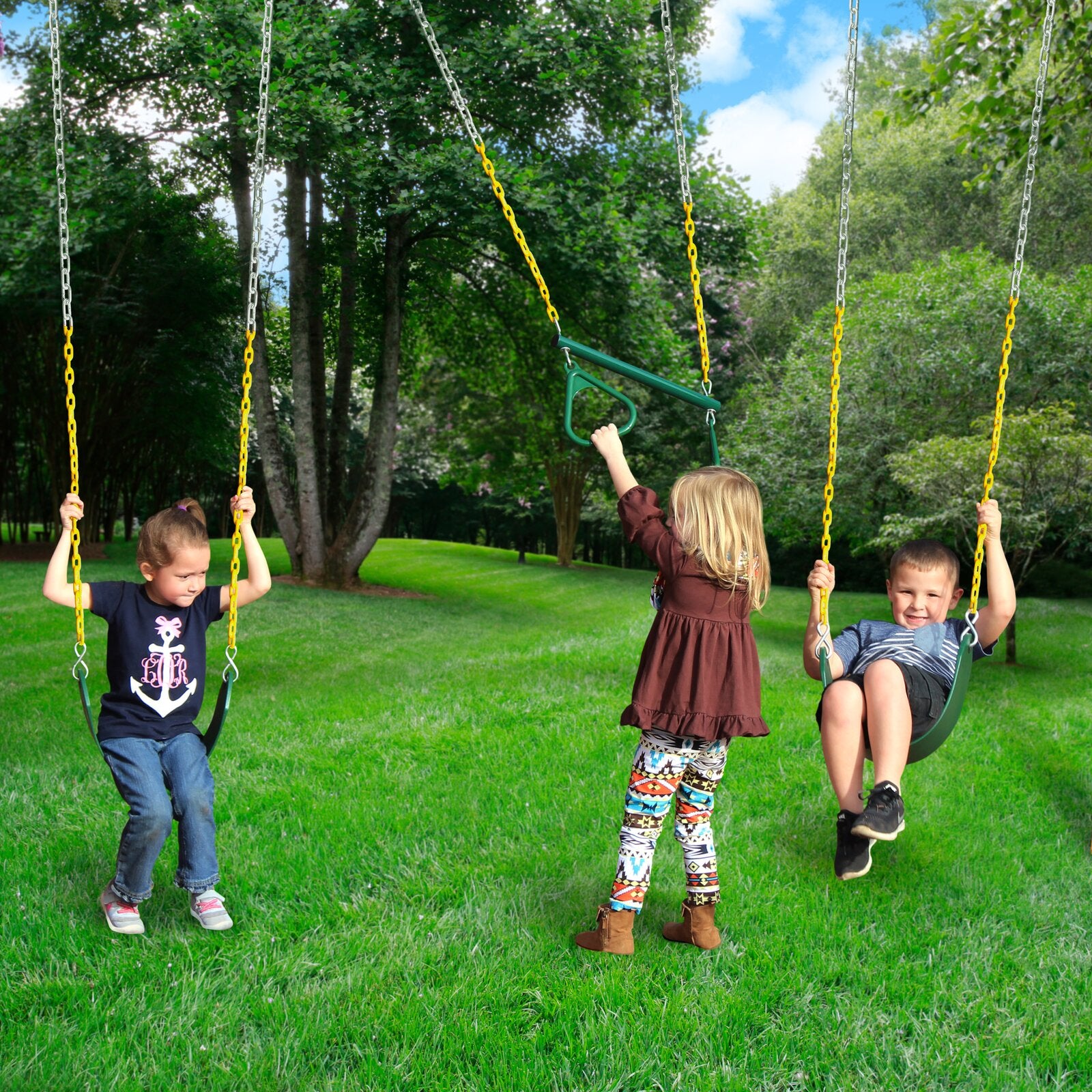 Three children playing on green and yellow belt swings in a grassy backyard with trees