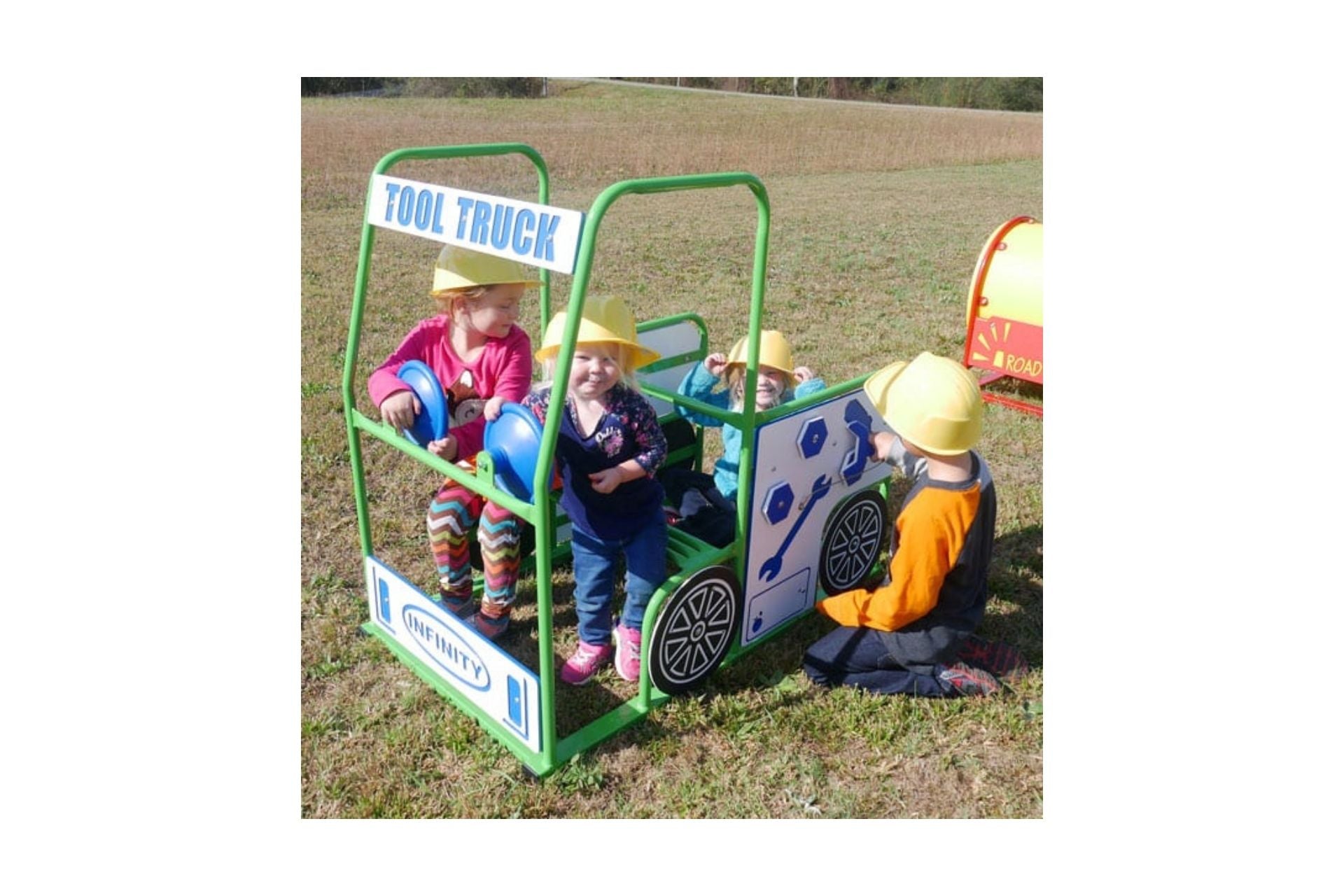 Tool Truck outdoor playset with green frame, blue steering wheels, and children wearing yellow helmets playing on grass