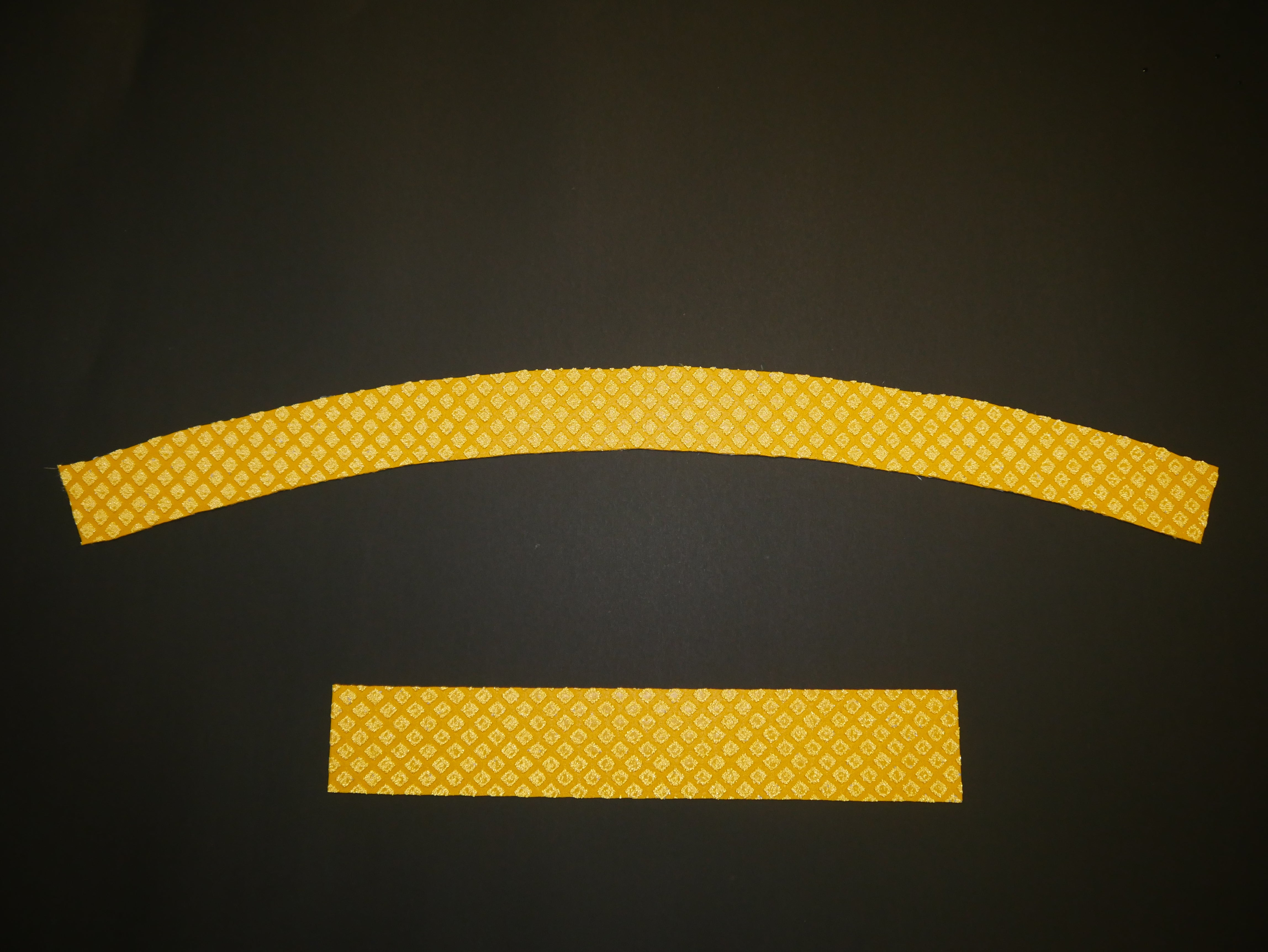 Curved and straight yellow reflective tricycle path stripes with diamond pattern on black surface