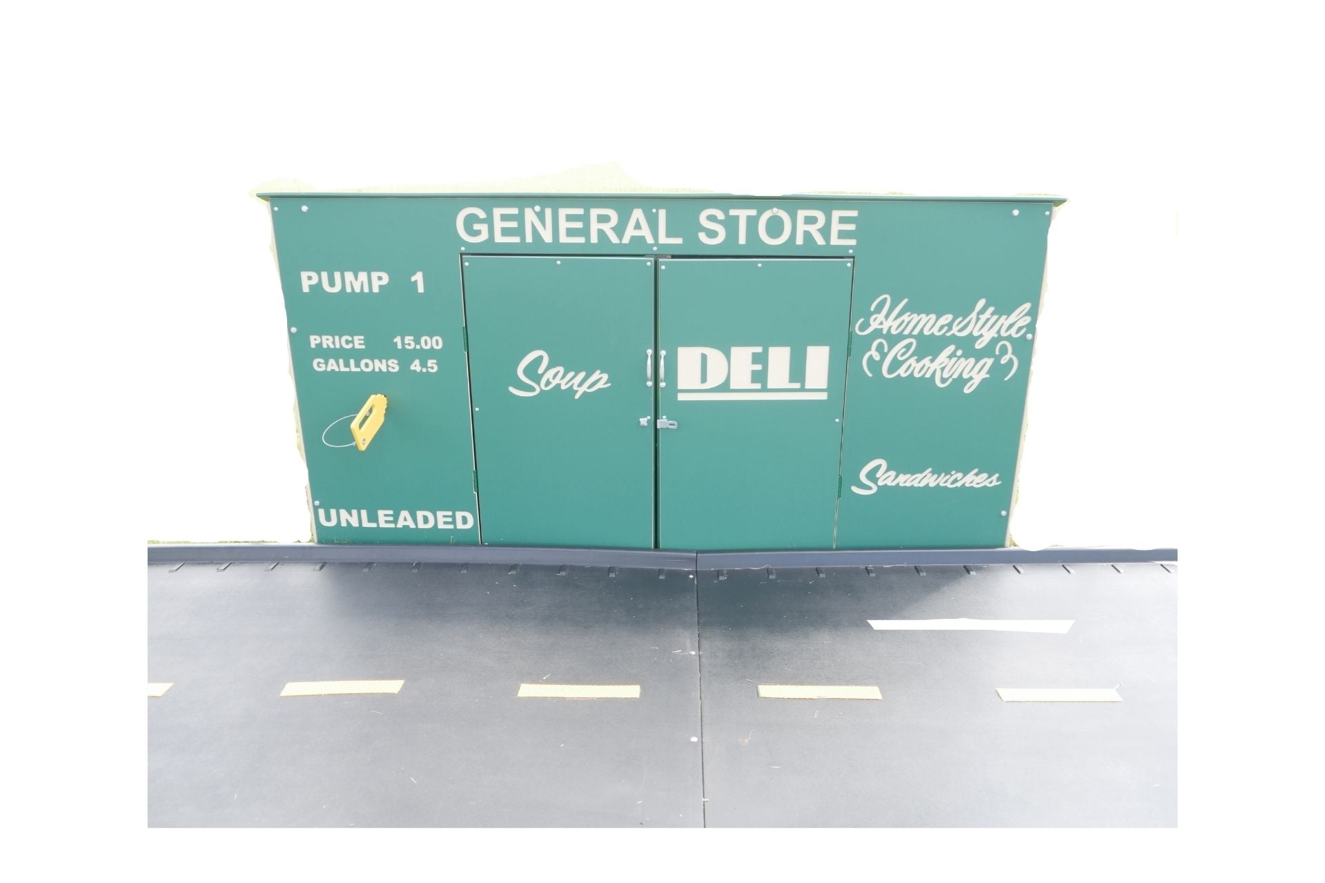 Green outdoor playhouse with general store theme, labeled doors for soup, deli, and homestyle cooking, on a play road surface