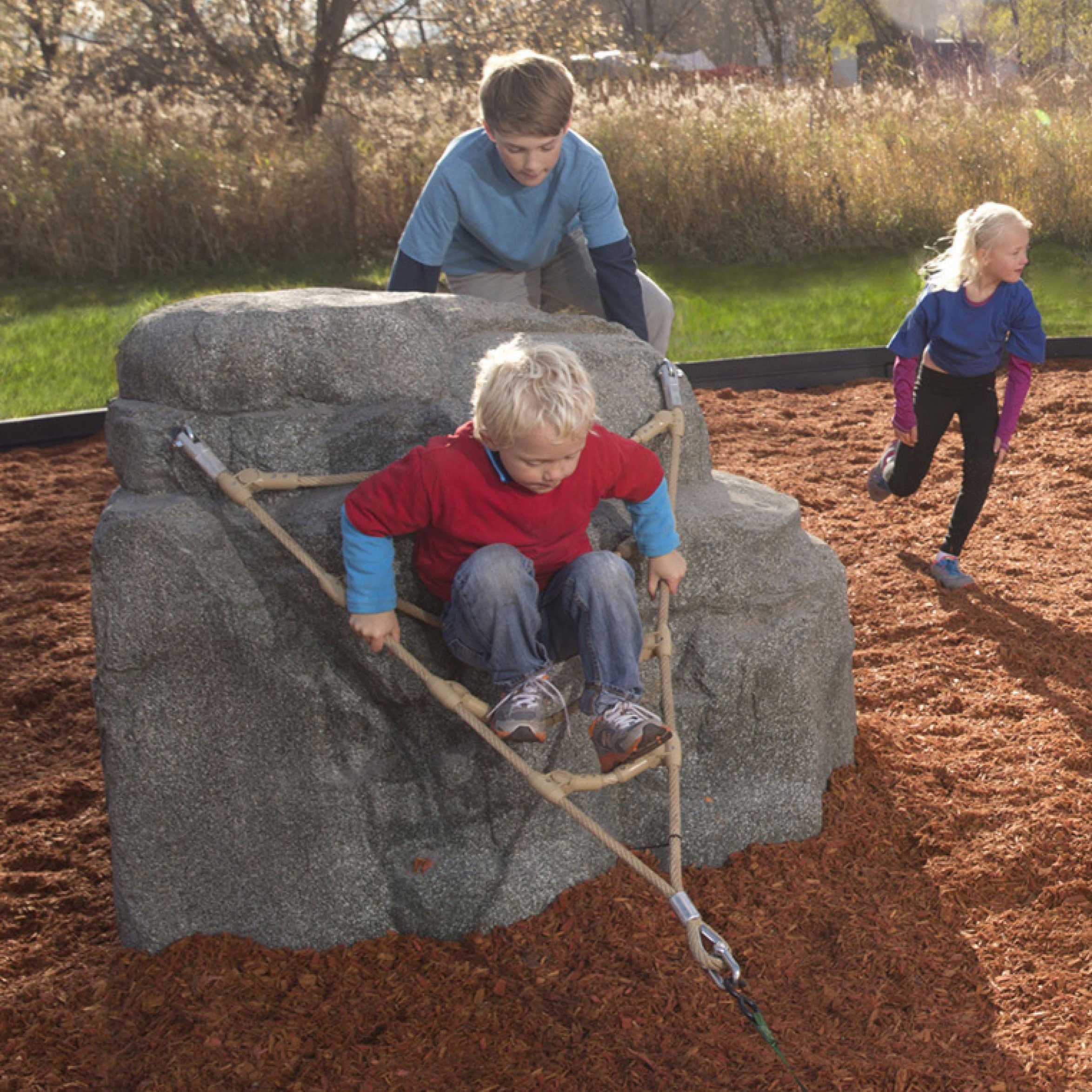 Children climbing the Nature Rocks Pike's Peak Climbing Rock with granite boulder and V ladder net in outdoor playground
