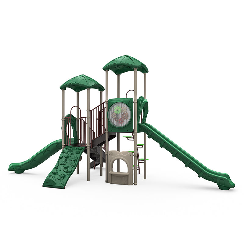Large green playground structure with two slides, rock climbing wall, gear panel, and multiple platforms with leaf-shaped roofs.