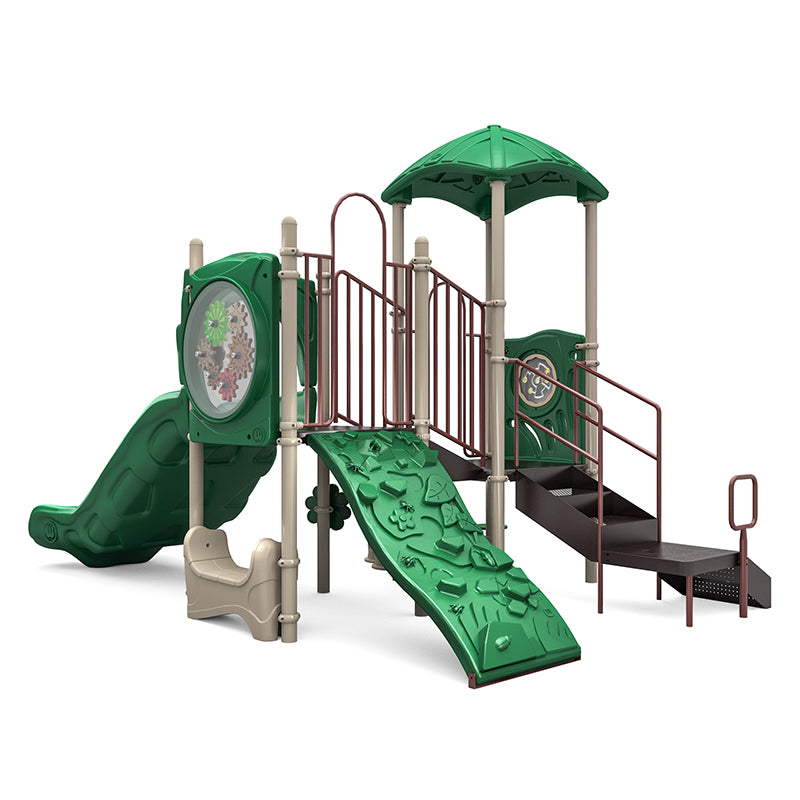 Playground structure with green roof, double slide, rock climber, interactive gear and maze panels, and stairs with handrails.