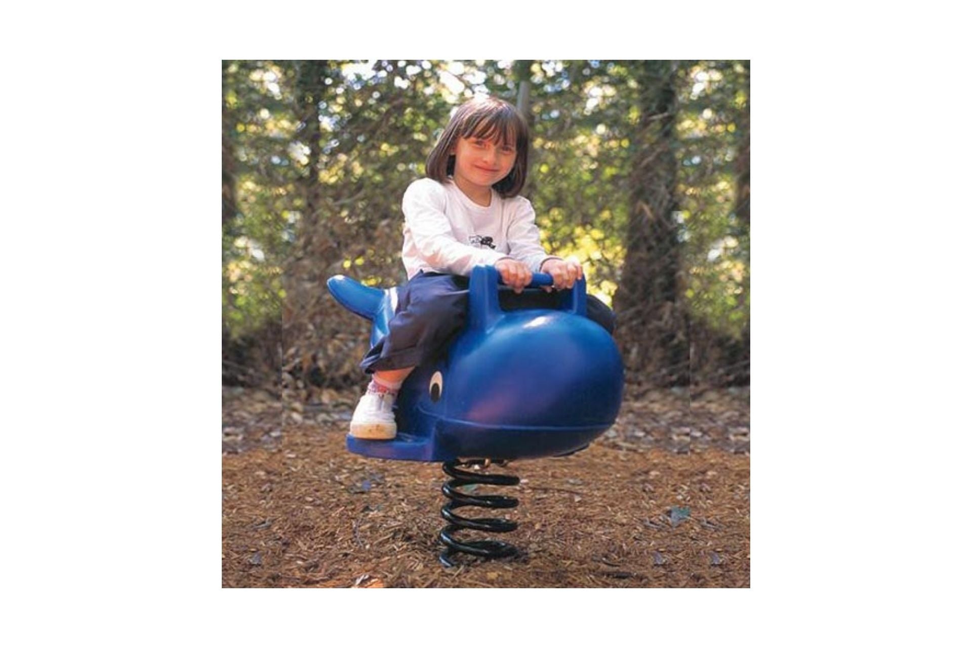 Child on blue Whale Spring Rider playground toy with spring base in outdoor wooded playground setting