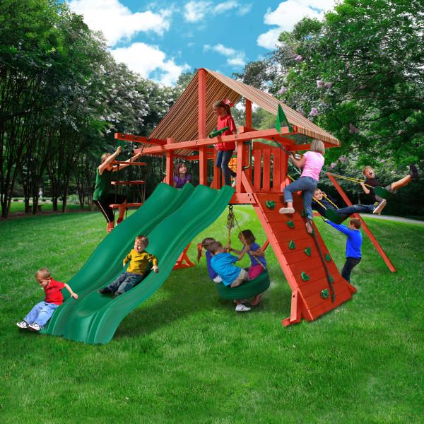 Sun Climber Extreme Wooden Swing Set with dual green Alpine Wave slides, redwood finish, climbing wall, tire swing, and multi-colored canopy