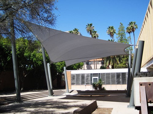 Gray hyperbolic sail shade with four angled metal columns providing angled outdoor sun protection