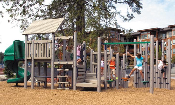 Outdoor playground structure with spiral slide, multiple climbing walls, platforms, and children playing on various elements