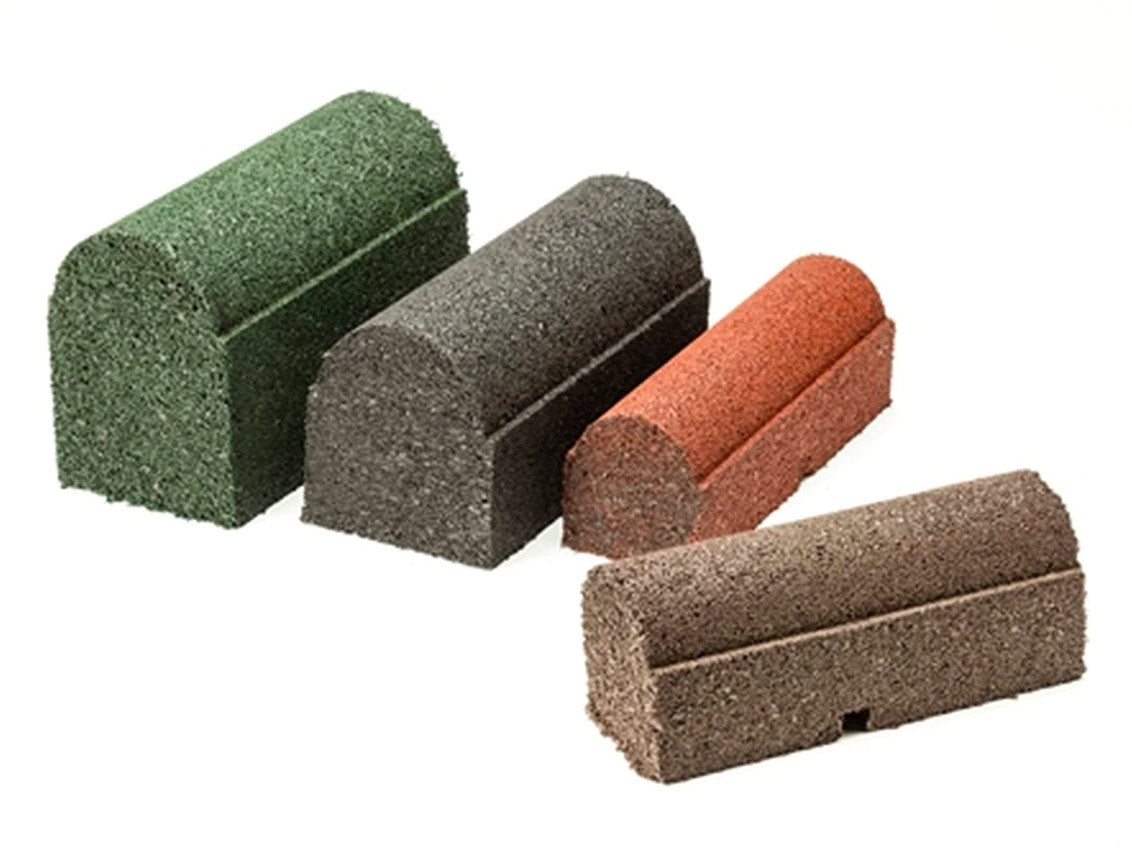 Four rubber playground border timbers in earthtone, black, redwood, and forest green with rounded tops and drainage ports